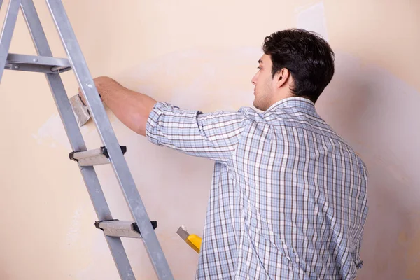 Hombre joven aplicando yeso en la pared en casa — Foto de Stock