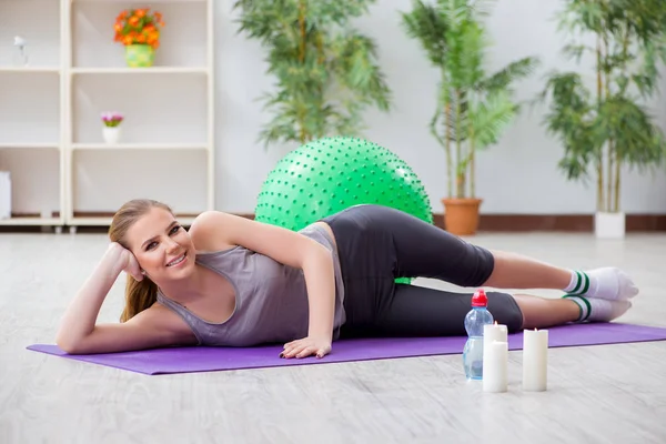 Young woman exercising with stability ball in gym
