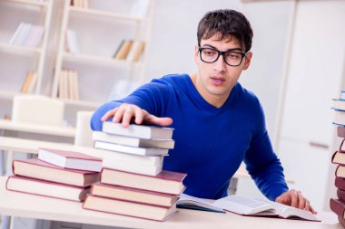 Erkek öğrenci üniversite kütüphanesinde sınava hazırlanıyor.