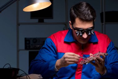 Bilgisayar uzmanı gece geç saatlerde bilgisayarı tamir ediyor.