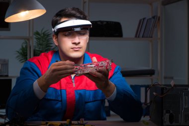 Bilgisayar uzmanı gece geç saatlerde bilgisayarı tamir ediyor.