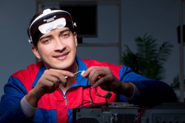 Bilgisayar uzmanı gece geç saatlerde bilgisayarı tamir ediyor.