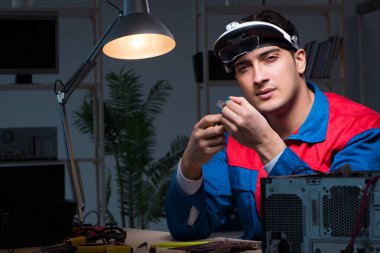 Bilgisayar uzmanı gece geç saatlerde bilgisayarı tamir ediyor.