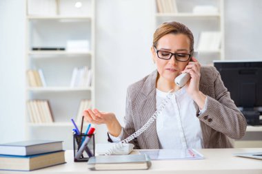 İş kadını çalışan ofis telefonundan konuşuyor.