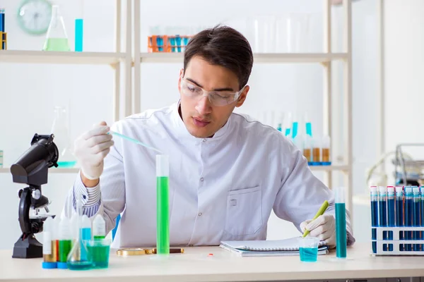 Jovem estudante de química que trabalha em laboratório em produtos químicos — Fotografia de Stock