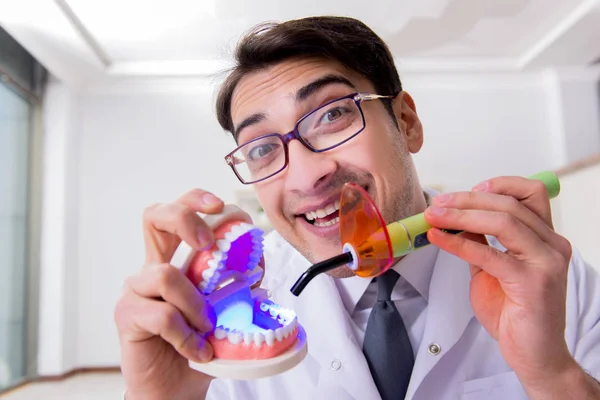 Dentista engraçado com luz de cura no conceito médico — Fotografia de Stock