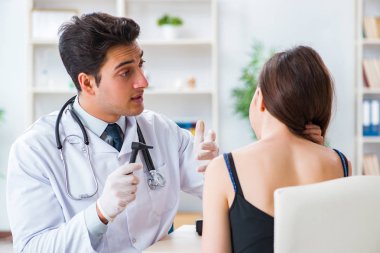 Doktor muayene sırasında hastaların kulaklarını kontrol ediyor.