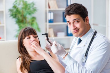 Doktor muayene sırasında hastaların kulaklarını kontrol ediyor.