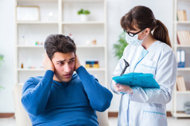 Doktor muayene sırasında hastaların kulaklarını kontrol ediyor.