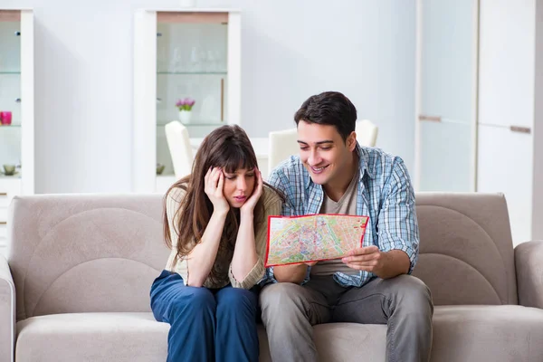 Ung familj diskuterar resplaner med karta — Stockfoto