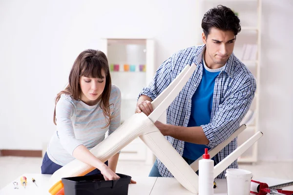 Wife helping husband to repair broken chair at home — Stock Photo, Image