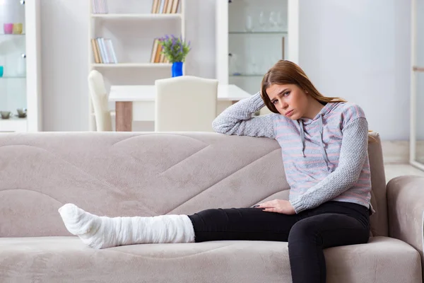 Junge Frau mit gebrochenem Bein zu Hause — Stockfoto