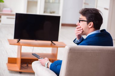 İş adamı ofiste televizyon izliyor.