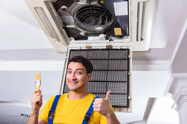 Repairman repairing ceiling air conditioning unit