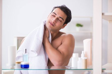 Genç adam banyoda çalışmak için hazırlanıyor.