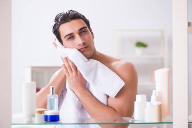 Genç adam banyoda çalışmak için hazırlanıyor.