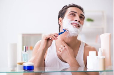 Genç yakışıklı adam sabah erkenden tıraş oluyor.