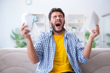 Ödeme yapması gereken faturalara kızgın bir adam.