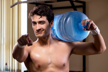 Büyük su şişeli kaslı adam.