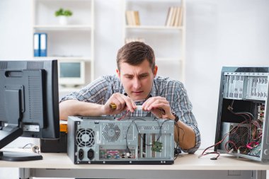 Genç teknisyen atölyede bilgisayar tamir ediyor.