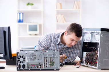 Genç teknisyen atölyede bilgisayar tamir ediyor.