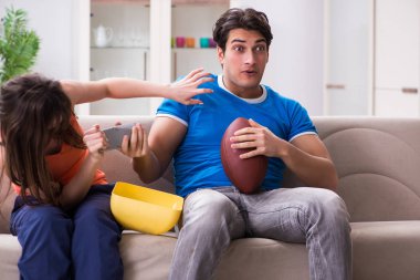 Adam karısıyla Amerikan futbolu seyrediyor.