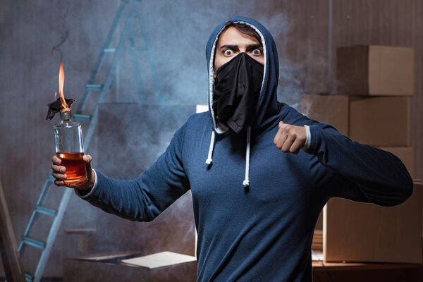 Мятежник с коктейлем Молотова в темной комнате