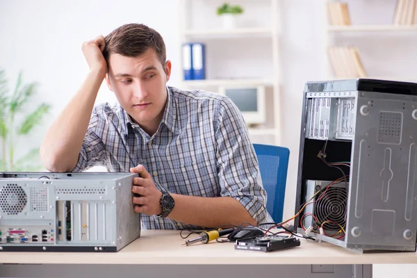 Genç teknisyen atölyede bilgisayar tamir ediyor.