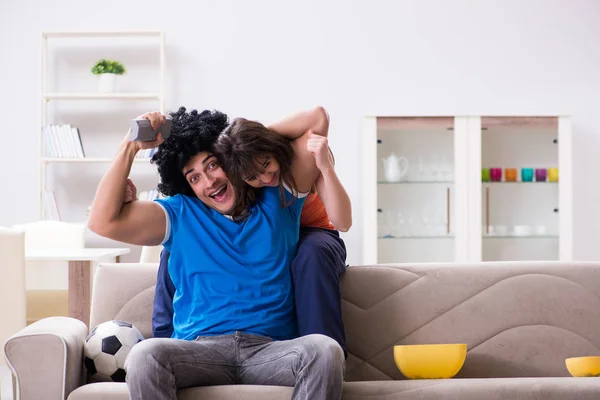 Jovem assistindo futebol com sua esposa em casa — Fotografia de Stock