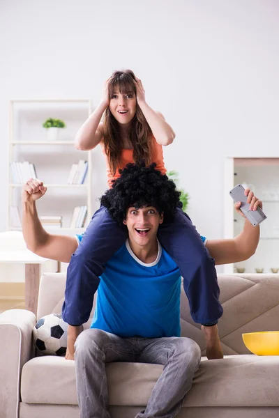 Jovem assistindo futebol com sua esposa em casa — Fotografia de Stock