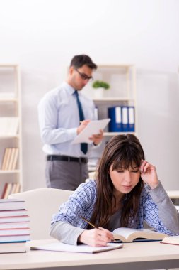 Erkek öğretim görevlisi bayan öğrenciye ders veriyor.