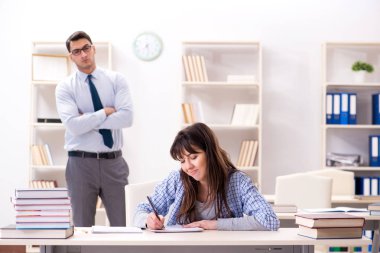 Erkek öğretim görevlisi bayan öğrenciye ders veriyor.