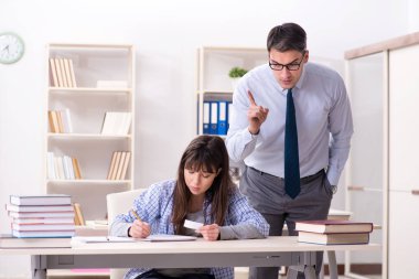 Erkek öğretim görevlisi bayan öğrenciye ders veriyor.