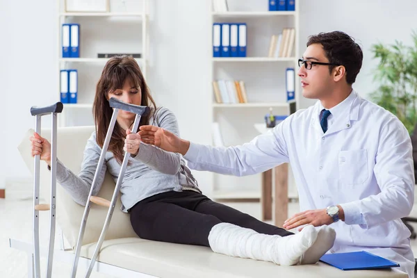 Médico examinando paciente com perna quebrada — Fotografia de Stock