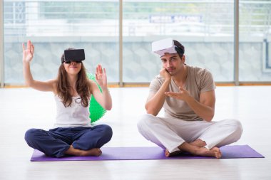 VR gözlüklü kadın ve erkek meditasyon yapıyor.