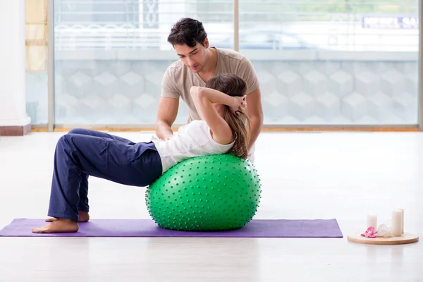 Treinador pessoal ajudando mulher no ginásio com bola de estabilidade — Fotografia de Stock