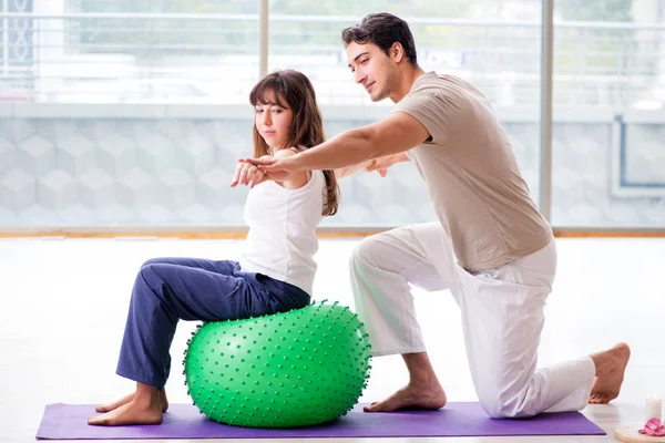 Personal Coach hilft Frau im Fitnessstudio mit Stabilitätsball — Stockfoto