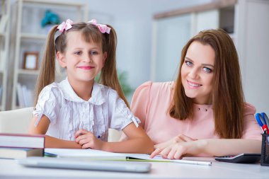 Anne, kızına ödevlerinde yardım ediyor.