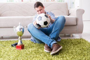 Evde futbol izleyen genç bir öğrenci.