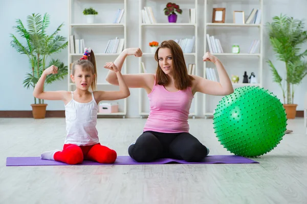 Menina e mãe se exercitando em casa — Fotografia de Stock