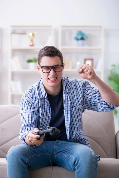 Молодой человек играет в компьютерные игры дома — стоковое фото