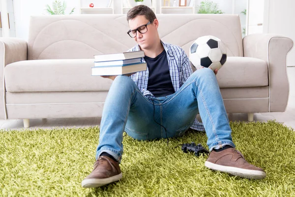 Jovem estudante tentando equilibrar estudar e jogar futebol — Fotografia de Stock