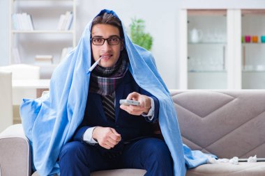 Çalışan işadamı grip olmuşken televizyon izliyor.