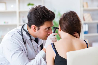 Doktor muayene sırasında hastaların kulaklarını kontrol ediyor.