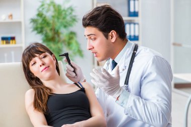 Doktor muayene sırasında hastaların kulaklarını kontrol ediyor.