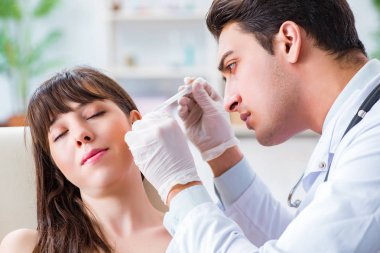 Doktor muayene sırasında hastaların kulaklarını kontrol ediyor.