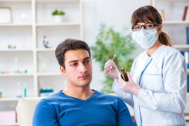 Doktor muayene sırasında hastaların kulaklarını kontrol ediyor.