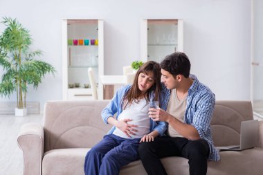 Pregnant woman with husband at home clipart