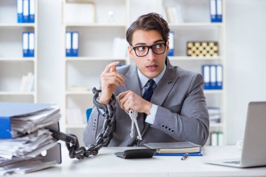 Ofis masasına zincirlenmiş meşgul bir çalışan.