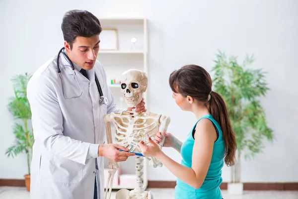 Doctor showing type of injury on skeleton to patient — Stock Photo, Image